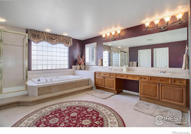 full bath featuring a textured ceiling, a sink, a shower stall, a bath, and double vanity