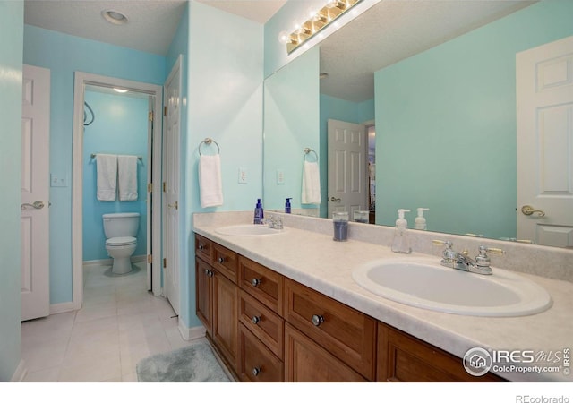 bathroom featuring a textured ceiling, double vanity, a sink, and tile patterned floors