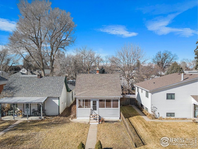 bungalow featuring driveway, a front lawn, roof with shingles, and a sunroom