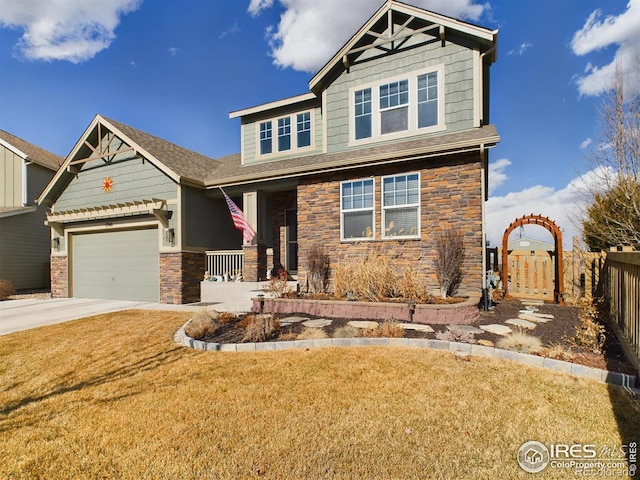 craftsman house with stone siding, fence, concrete driveway, and a front yard