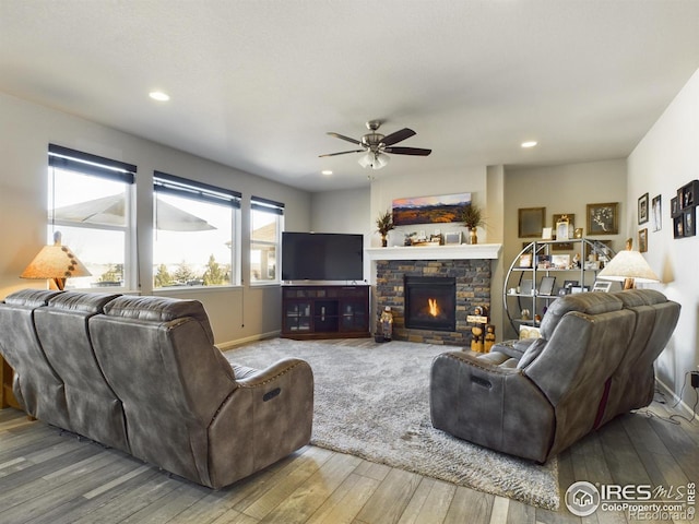 living area with recessed lighting, a ceiling fan, a stone fireplace, baseboards, and hardwood / wood-style flooring