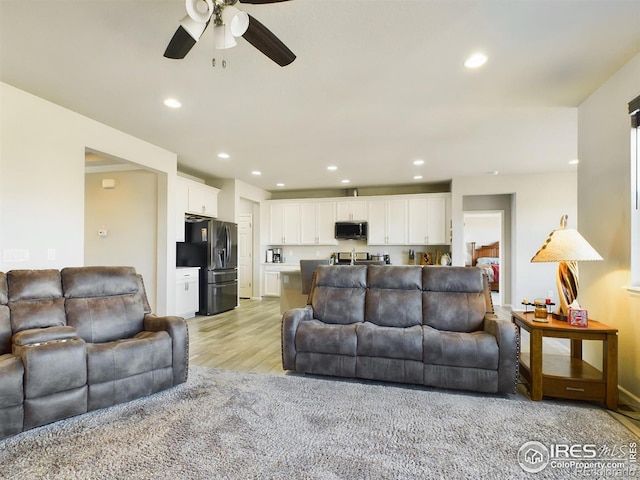 living room with light wood finished floors, a ceiling fan, and recessed lighting