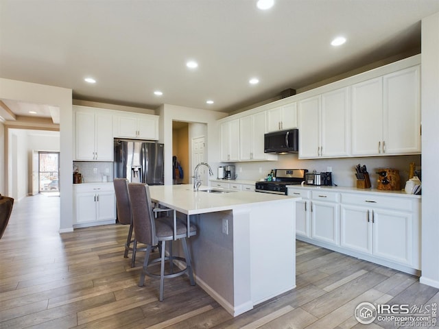 kitchen featuring appliances with stainless steel finishes, white cabinetry, and a center island with sink