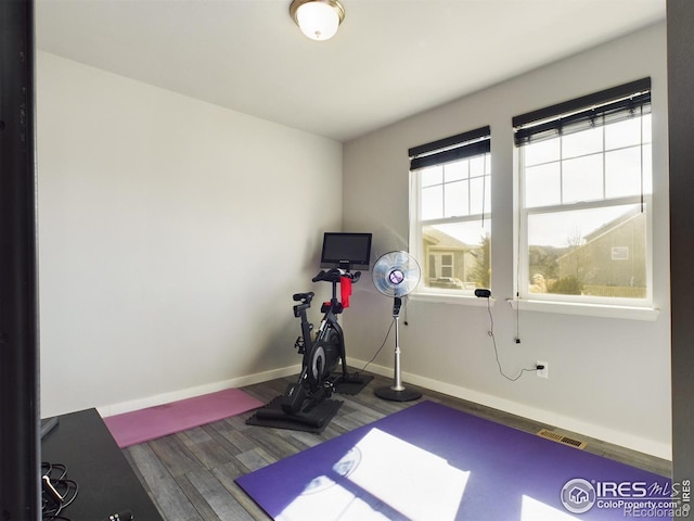 workout room featuring visible vents, baseboards, and wood finished floors