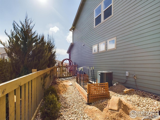 view of property exterior featuring central AC unit and a garden