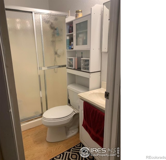 full bathroom featuring vanity, a stall shower, wood finished floors, and toilet