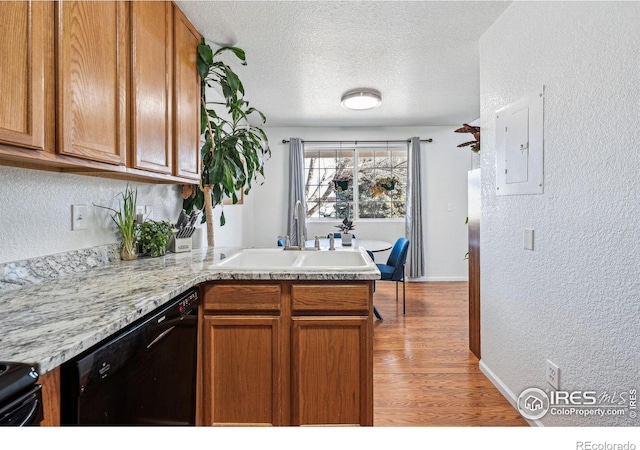 kitchen featuring a peninsula, black dishwasher, brown cabinetry, and a textured wall