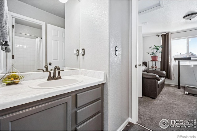 bathroom featuring a textured ceiling, a textured wall, a shower with shower curtain, and vanity