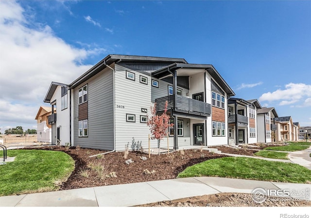 view of front of home with a front lawn, a residential view, and a balcony