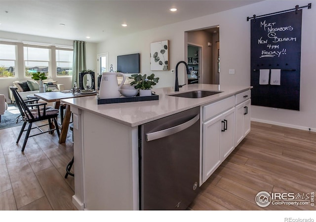 kitchen with a sink, light wood-style flooring, white cabinets, and stainless steel dishwasher