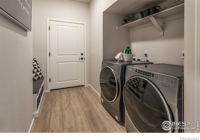 clothes washing area featuring baseboards, laundry area, light wood finished floors, and washer and dryer