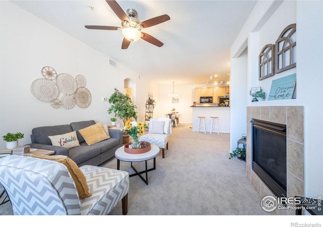 living room with a ceiling fan, carpet, visible vents, and a fireplace