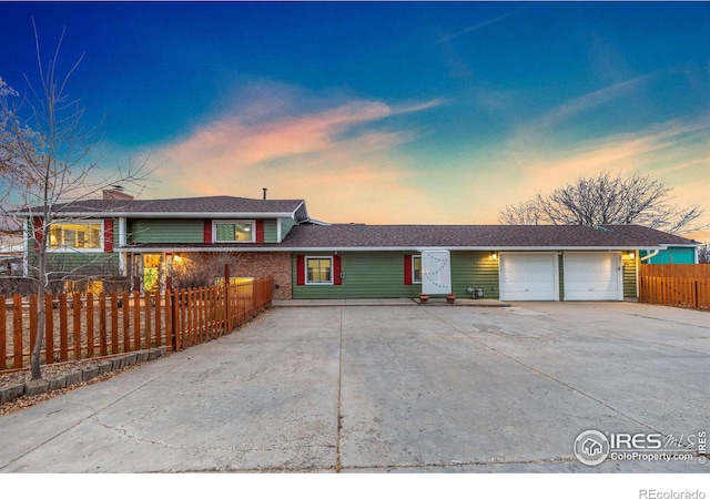 view of front of home with a garage, concrete driveway, and fence