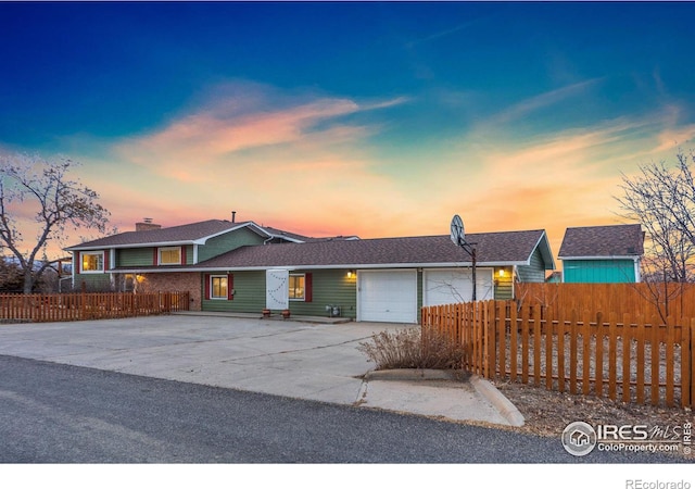 ranch-style house featuring driveway, a fenced front yard, and an attached garage