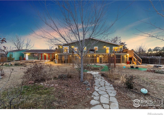 back of property at dusk featuring a patio area and stairs