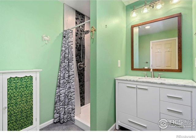 full bath featuring a stall shower, vanity, and baseboards