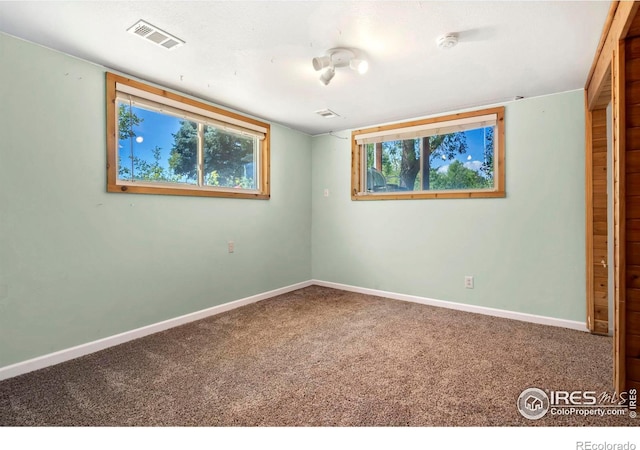 carpeted spare room featuring visible vents and baseboards