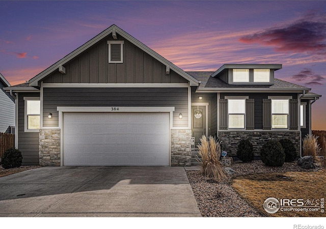 view of front of home featuring a garage, stone siding, board and batten siding, and concrete driveway