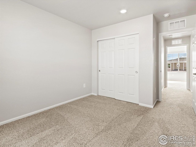 unfurnished bedroom with carpet, a closet, visible vents, and baseboards