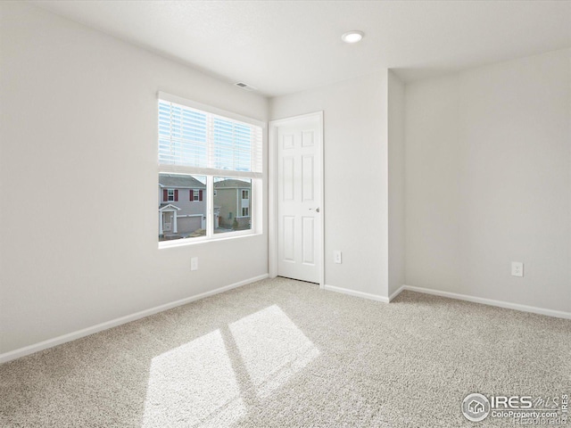 carpeted spare room with visible vents and baseboards