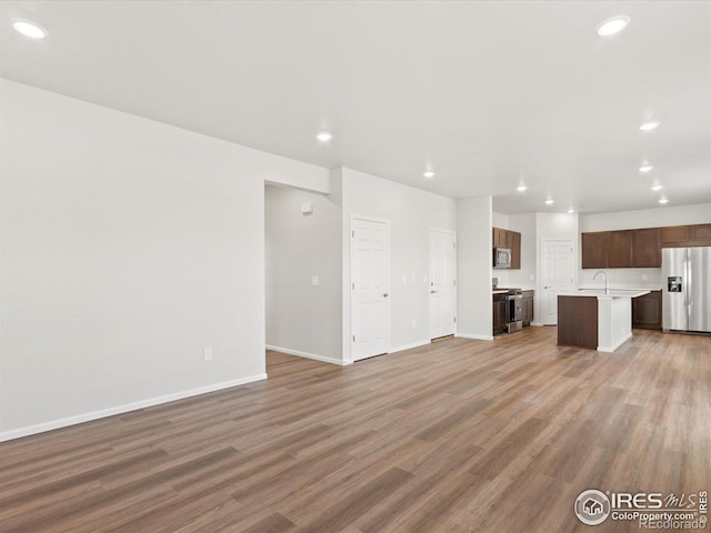 unfurnished living room featuring baseboards, wood finished floors, and recessed lighting