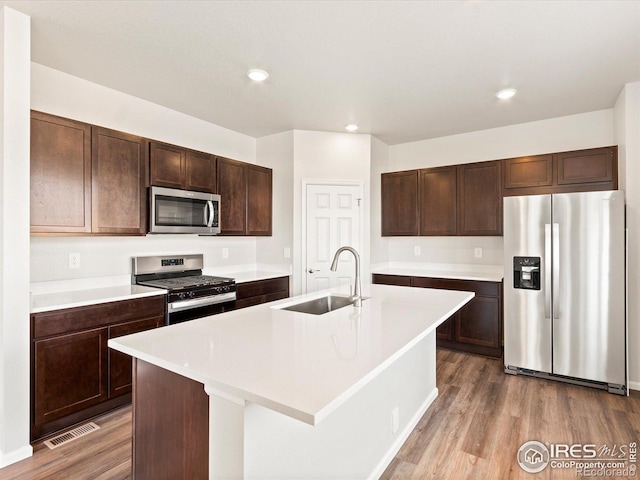 kitchen with stainless steel appliances, wood finished floors, a sink, and visible vents