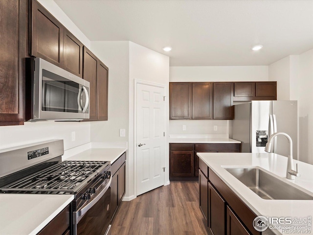 kitchen with stainless steel appliances, dark brown cabinets, dark wood-type flooring, and a sink