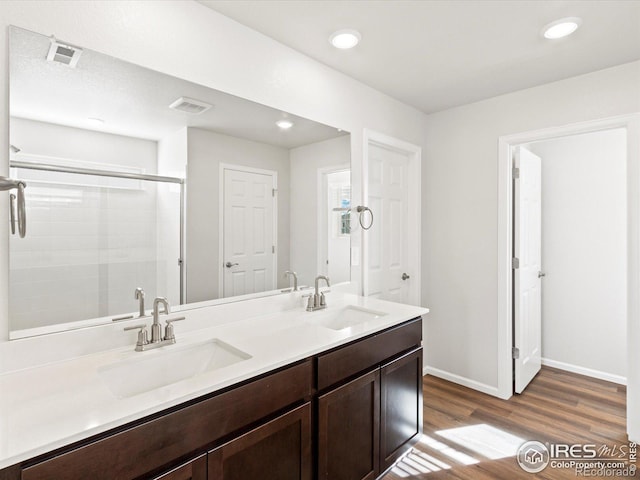 bathroom featuring a shower stall, visible vents, a sink, and wood finished floors