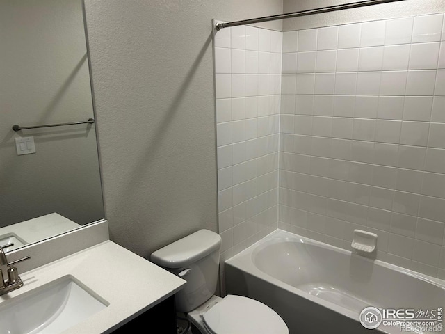 full bathroom with washtub / shower combination, a textured wall, vanity, and toilet