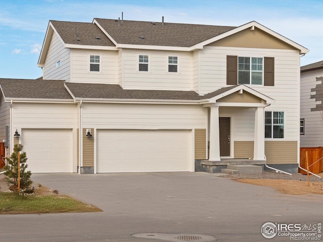 view of front facade featuring a shingled roof, driveway, an attached garage, and fence