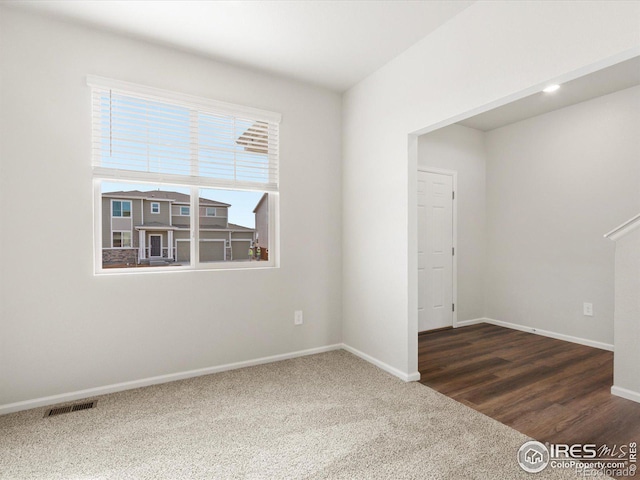 unfurnished room with carpet floors, visible vents, and baseboards