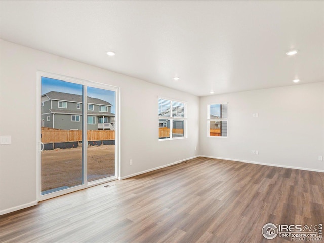 unfurnished room with baseboards, wood finished floors, and recessed lighting