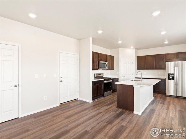 kitchen featuring stainless steel appliances, a sink, dark brown cabinets, and dark wood-style floors