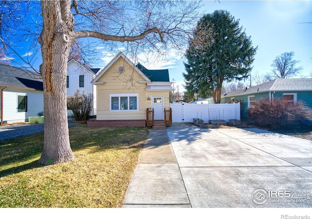 bungalow-style home with fence and a front lawn