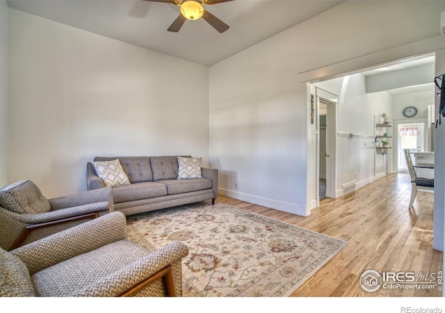 living area featuring ceiling fan, baseboards, and wood finished floors