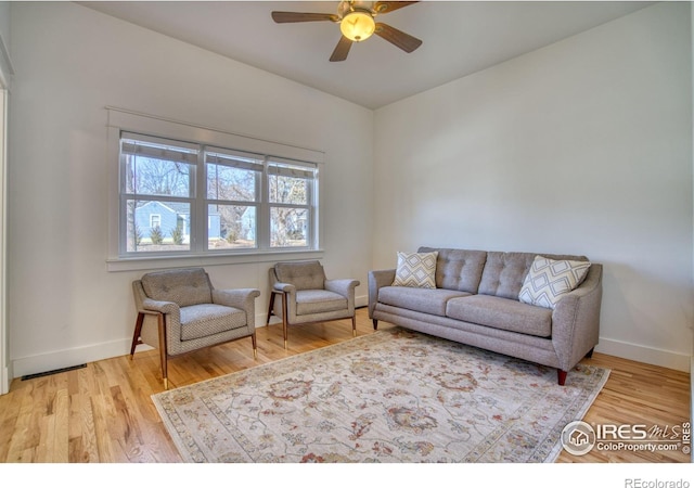 living room featuring wood finished floors, a ceiling fan, and baseboards