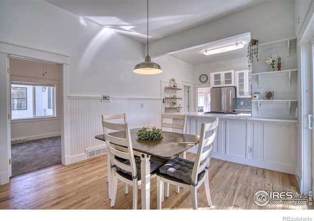 dining room featuring a wainscoted wall, visible vents, and light wood finished floors