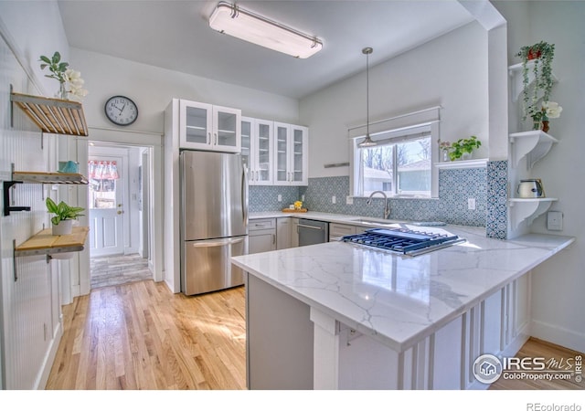 kitchen with open shelves, appliances with stainless steel finishes, glass insert cabinets, white cabinetry, and a peninsula