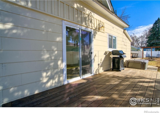 wooden terrace featuring a hot tub, fence, and grilling area