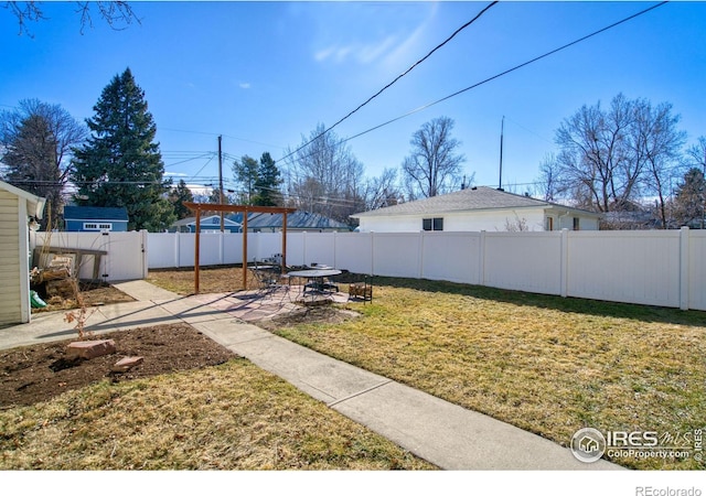 view of yard with a patio, a fenced backyard, and a gate