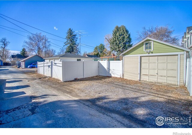 detached garage with fence and dirt driveway