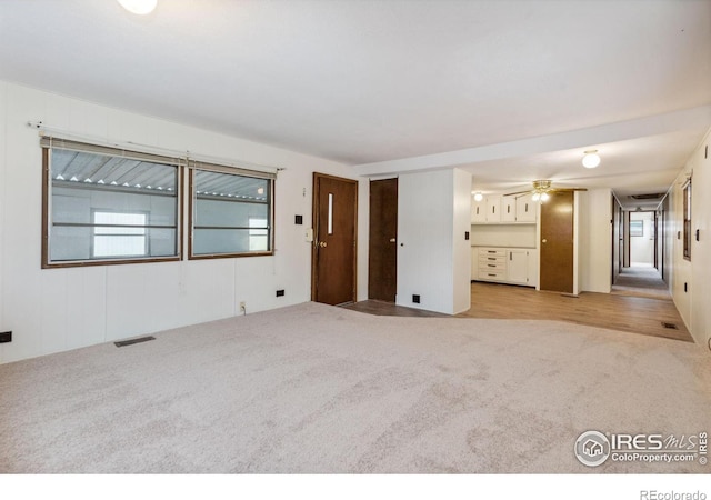 carpeted spare room with ceiling fan and visible vents