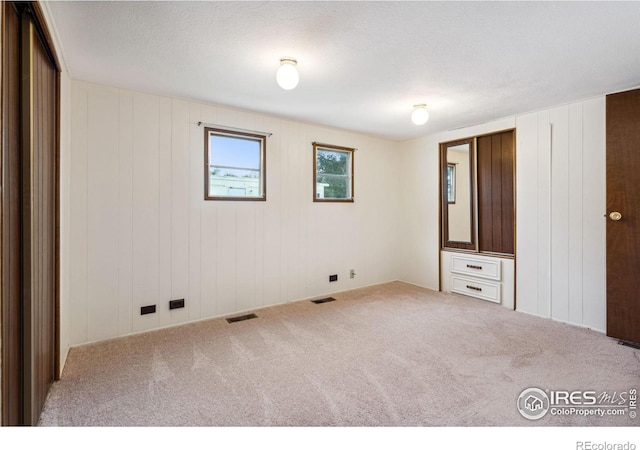 unfurnished bedroom featuring carpet, visible vents, and a textured ceiling