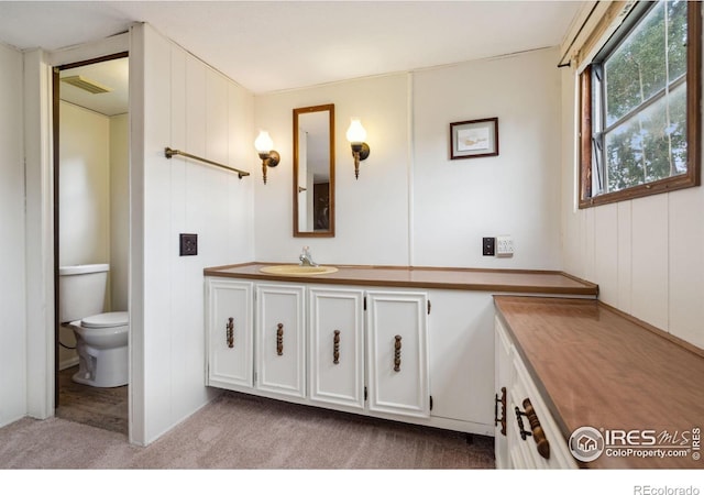 bathroom with toilet, vanity, and visible vents