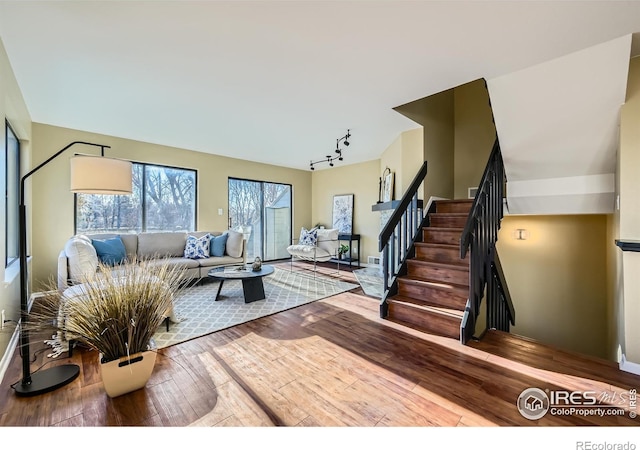 living area with rail lighting, stairway, and hardwood / wood-style floors