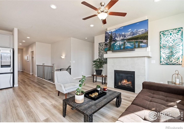 living room featuring light wood-type flooring, a fireplace, baseboards, and recessed lighting