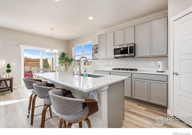 kitchen featuring appliances with stainless steel finishes, a sink, light wood-style flooring, and gray cabinetry