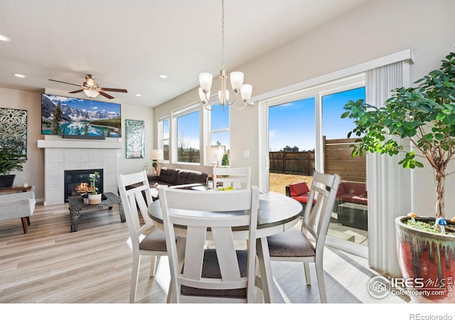 dining area featuring a ceiling fan, a tiled fireplace, light wood-style flooring, and recessed lighting