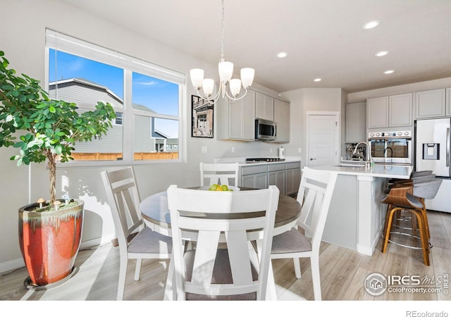 dining room featuring recessed lighting, light wood finished floors, and an inviting chandelier