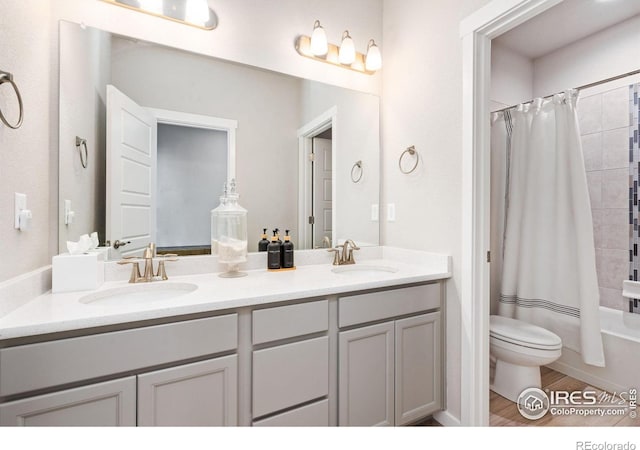 full bath with double vanity, shower / bath combo with shower curtain, a sink, and toilet